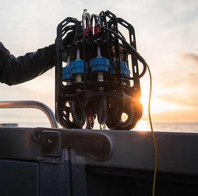 Ascension microplastics depth sampler sits on the side of a boat railing with the setting sun in the background