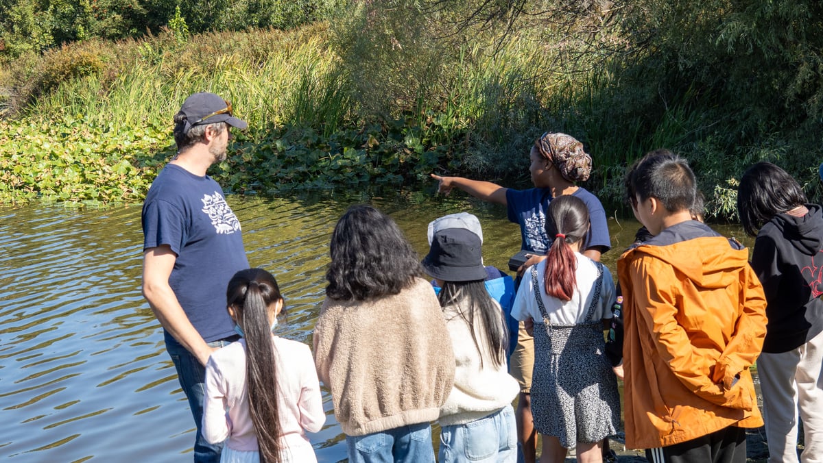 Students gather around as Water Rangers instructors teach about water quality 